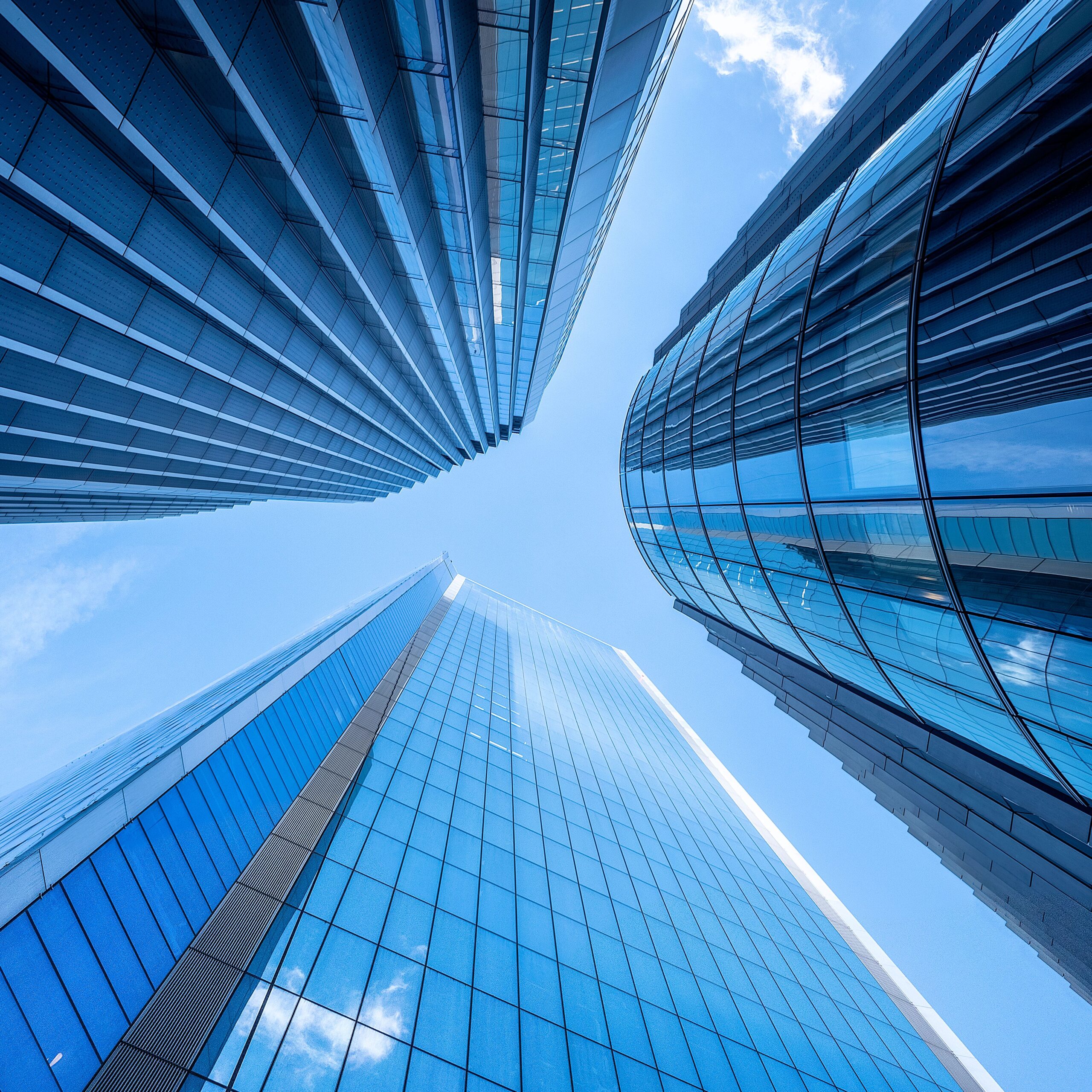 Striking upward view of modern skyscrapers against a clear London sky, showcasing urban architectural elegance.